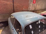 an old car parked in a parking lot next to a brick wall
