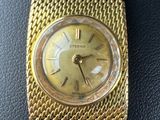 a close up of a gold wrist watch on a black surface