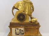 a gold statue of a man with a clock on top of a table