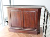 une armoire en bois posée sur un parquet, près d'une fenêtre