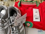 two pairs of shoes and a bag sitting on a bed