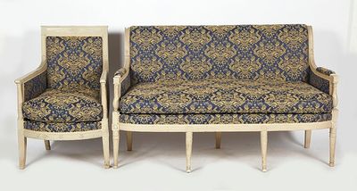 two chairs and a couch in a room with a white wall