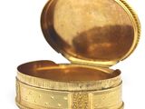 a small gold box with a lid on a white surface