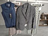 two suits hanging on a clothes rack in a room