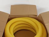une boîte contenant un tuyau jaune, posée sur une surface blanche