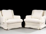 pair of white upholstered chairs with white cushions on a black background