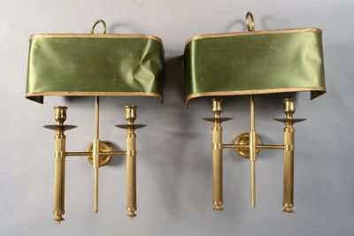 pair of brass sconces with green velvet shades on them