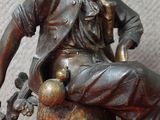 une statue représentant un homme assis sur une souche d'arbre