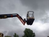 a man on a cherry picker working on a cloudy day