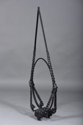 black and white photograph of a sculpture with a long chain hanging from it ' s neck