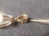 a close up of a white pearl and gold bow brooch