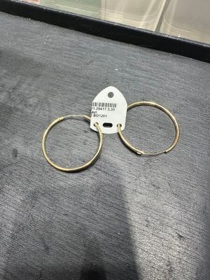une paire de boucles d'oreilles créoles en or posée sur une table