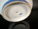 a close up of a white and blue vase on a table