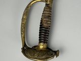a gold colored sword with a black handle on a white wall