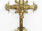 a gold cross with a bird on top of it next to a white wall