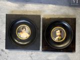 two framed portraits of a woman and a man on a wall