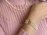 woman wearing a pink sweater and pearl bracelets and a pearl necklace