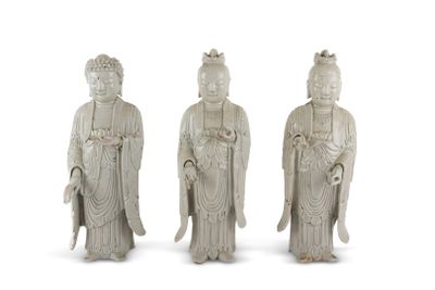 three white statues of asian people standing next to each other on a white surface