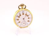 a gold pocket watch on a clear stand on a white surface