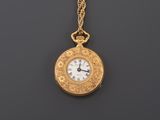 an antique gold pocket watch with a chain on a black background