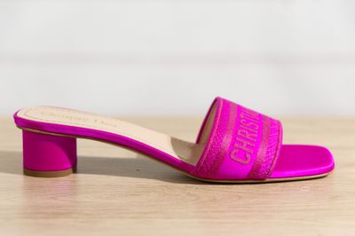 a pink muler sandal with a block heel on a wooden surface