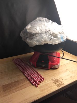 un objet rouge posé sur une table en bois, recouvert d'un sac en plastique
