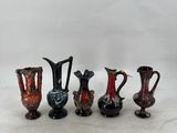 five different colored vases are lined up on a white surface