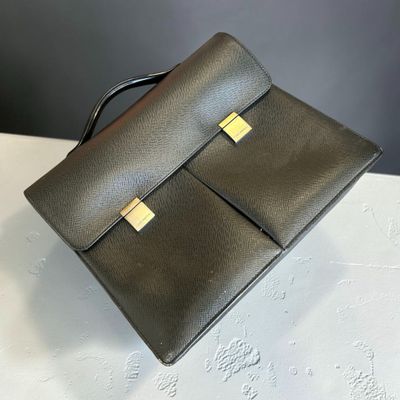 un sac à main en cuir noir posé sur une table blanche