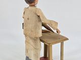 an image of a small wooden figure of a man sitting at a desk