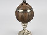 une urne ancienne en argent et en bois, munie d'un couvercle et posée sur un socle