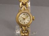 an image of a gold wrist watch on a clear acrylic stand