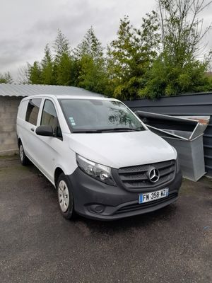 une camionnette blanche garée sur un parking à côté d'un bâtiment