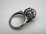 an image of a silver ring with a red bead on it