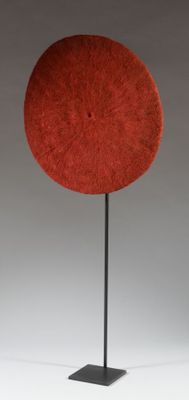 an orange hat on a black stand against a white background