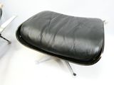 un fauteuil et un repose-pieds en cuir noir sur fond blanc