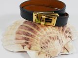 black leather bracelet with gold buckle and shell on white background