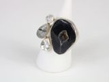 a close up of a ring with a black stone surrounded by diamonds