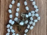 necklace with white beads and a cross on a wooden surface