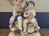a figurine of two children sitting on top of a book