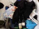 a bag full of clothes and bottles of wine on a bed