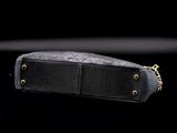 black leather purse with gold chain on a black background