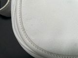 a close up of a white purse on a table