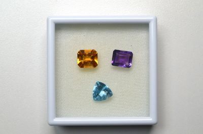 trois pierres précieuses de couleurs différentes, encadrées de blanc, sur un fond blanc