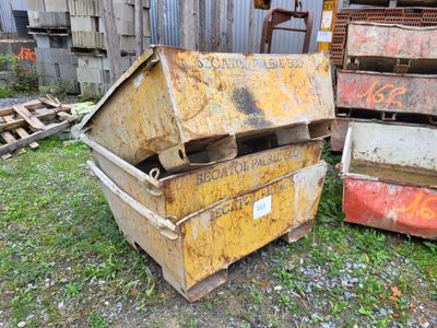 a yellow dumpster sitting in the grass next to a pile of other junk