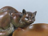 a statue of a cat that is laying on top of a bowl