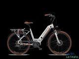 un vélo électrique blanc avec une selle marron sur fond noir