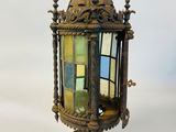 an old fashioned lantern hanging from the ceiling with a stained glass window