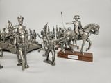three silver figurines of men on horses and a man on a horse