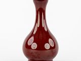 un vase rouge posé sur une surface blanche