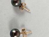 a pair of black pearl earrings on a white surface